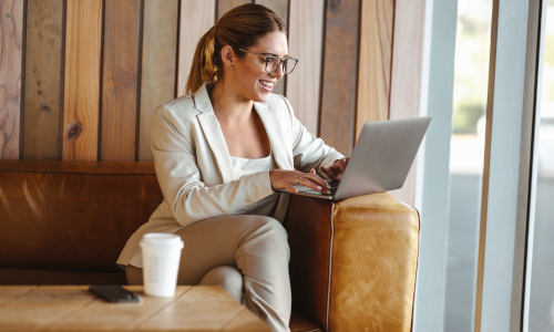 Young woman relaxing on a couch with a laptop and coffee, enjoying the flexibility of earning an affordable online degree from Texas Tech University. Experience the convenience of online learning with TTU’s flexible programs designed for busy students.